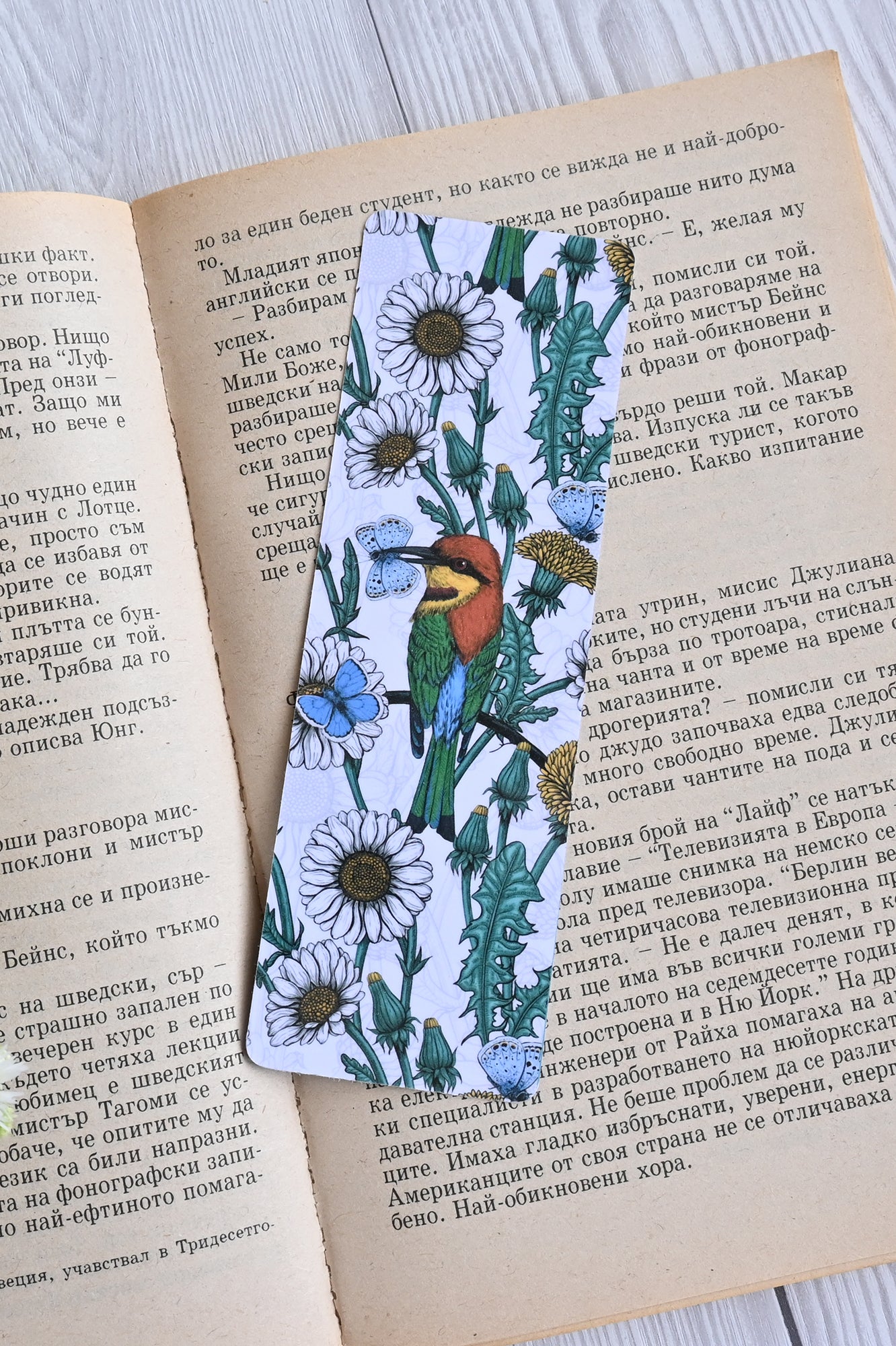 photo featuring a laminated bookmark with printed illustration of Bee-eaters and daisies