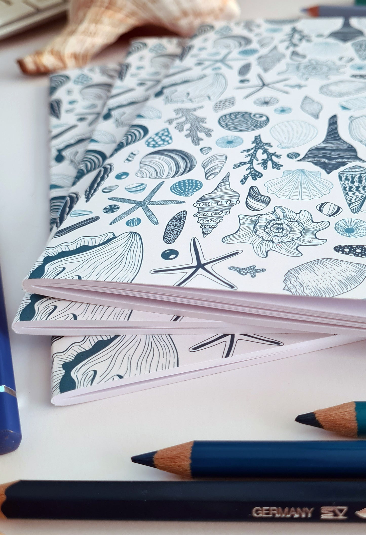 photo of 3 hand-made notebooks with hand-painted sea shells pattern print on the cover