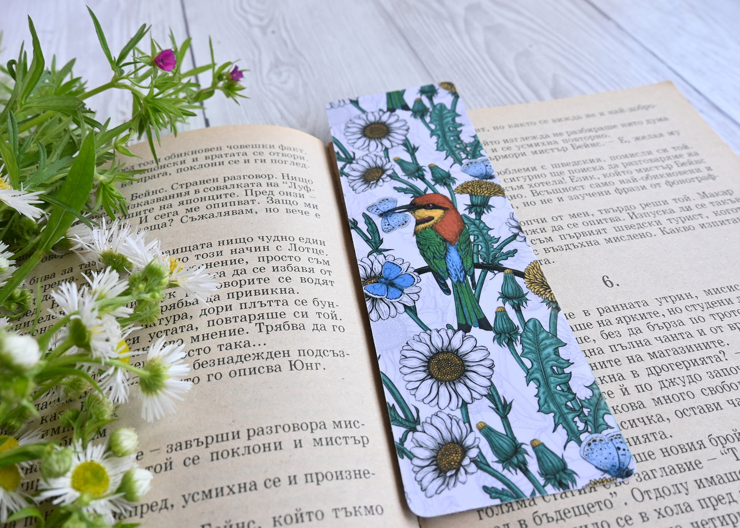photo featuring a laminated bookmark with printed illustration of Bee-eaters and daisies
