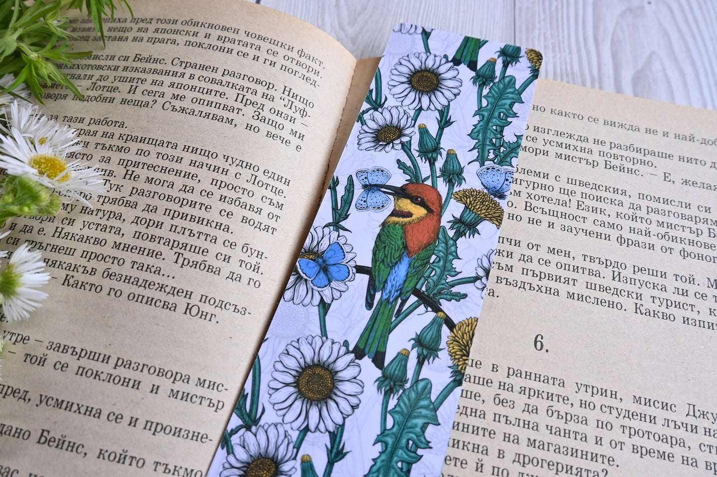 photo featuring a laminated bookmark with printed illustration of Bee-eaters and daisies