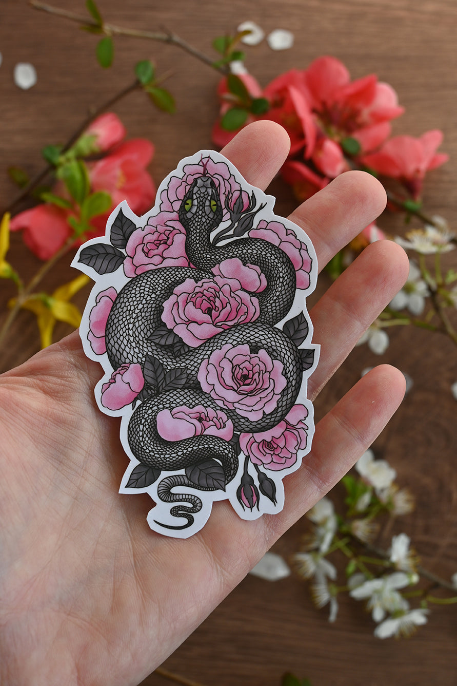 photo of a laminated paper sticker featuring illustration of a snake among rose flowers