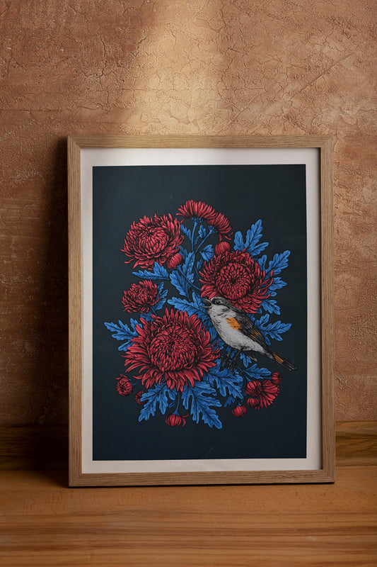 Framed print with red chrysanthemums and blue leaves and bird on a dark background, against a brown wall.
