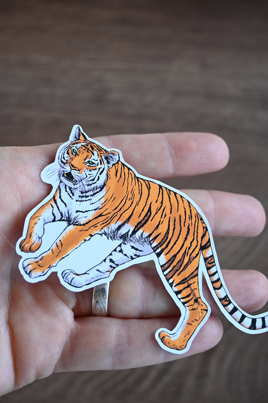 Sticker of a tiger held in a hand against a neutral background
