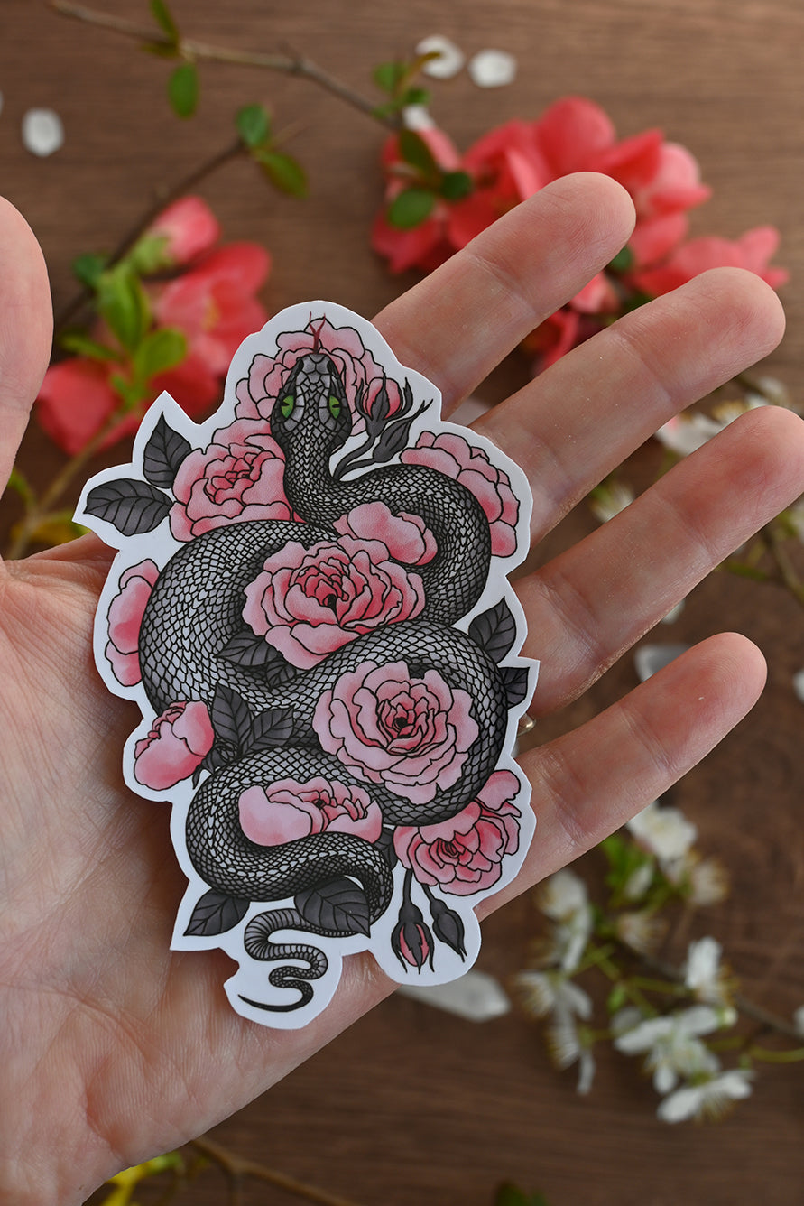 photo of a laminated paper sticker featuring illustration of a snake among rose flowers