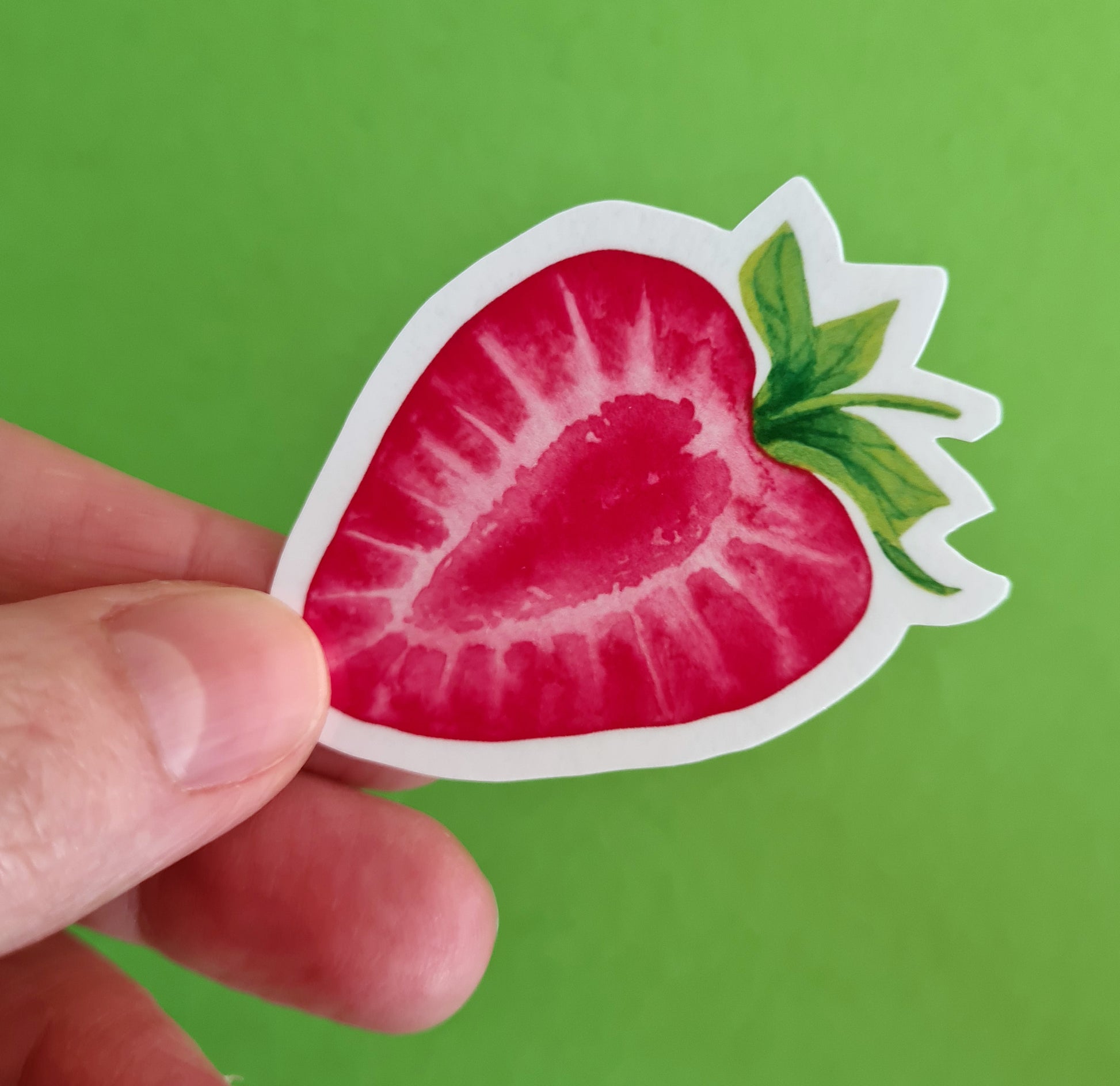 photo of a sticker featuring a strawberry slice painted with watercolors