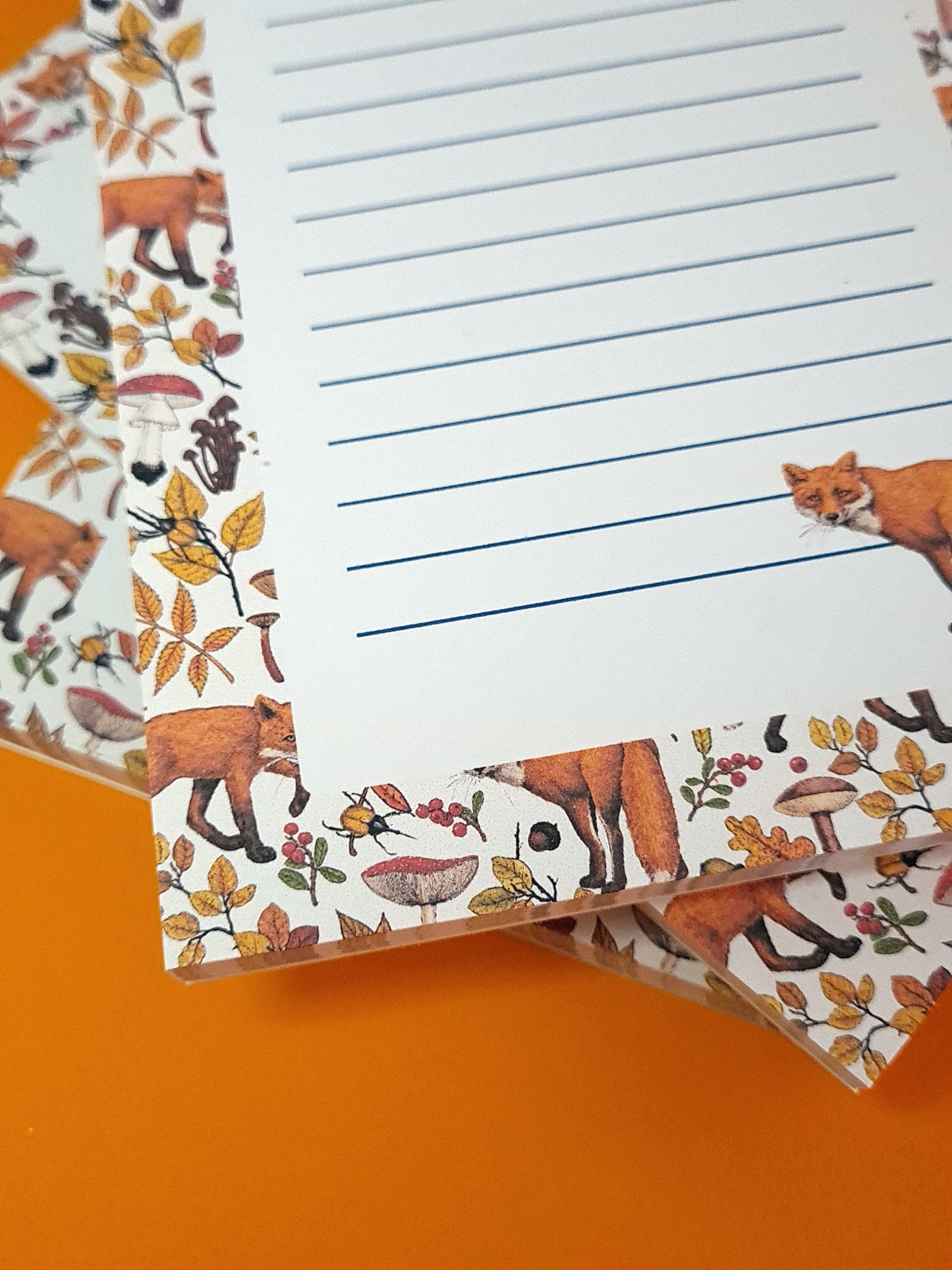 corner close up of notepad ilustrated with hand-painted red Foxes and autumn flora