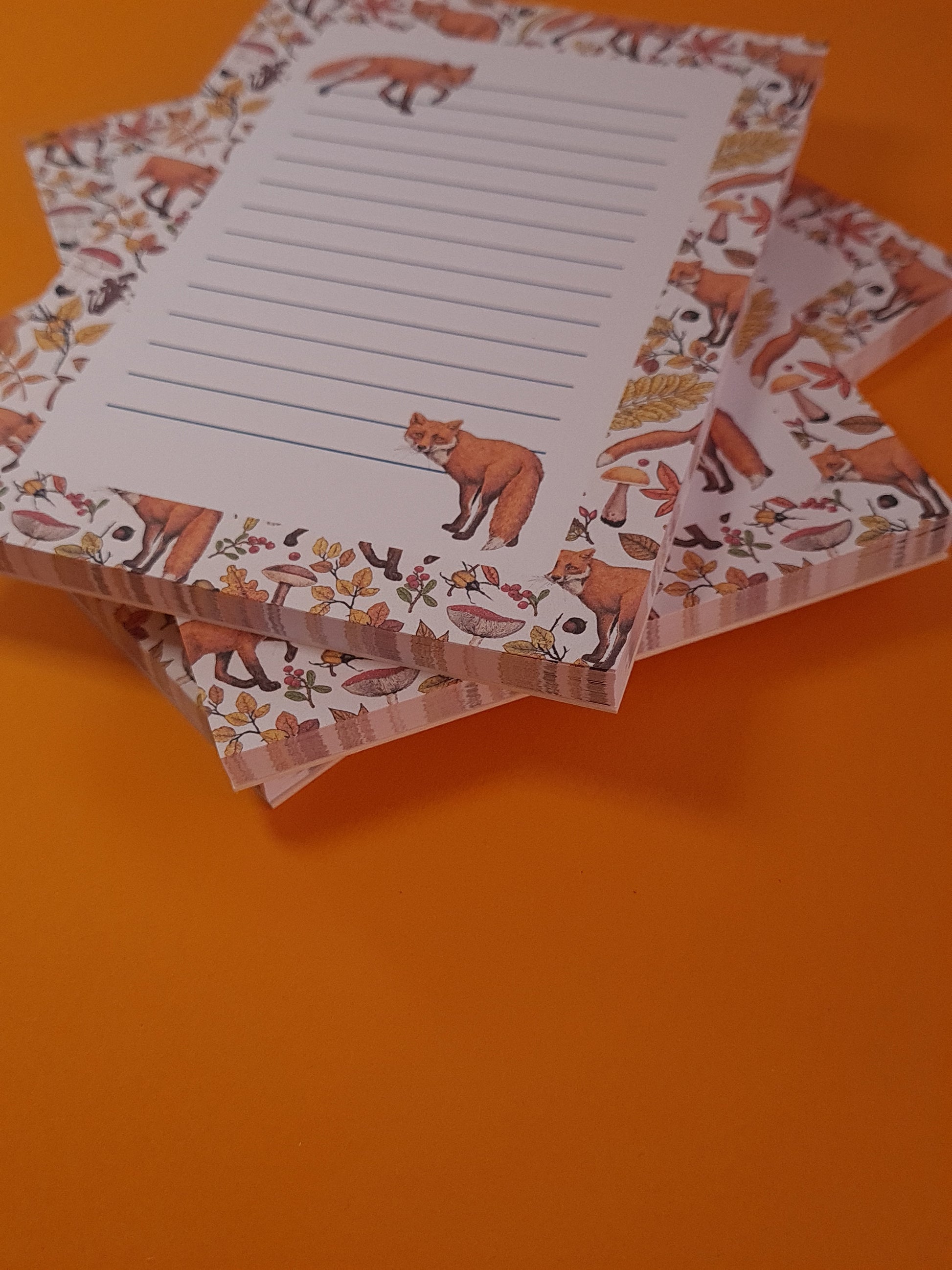 corner close up of notepads ilustrated with hand-painted red Foxes and autumn flora