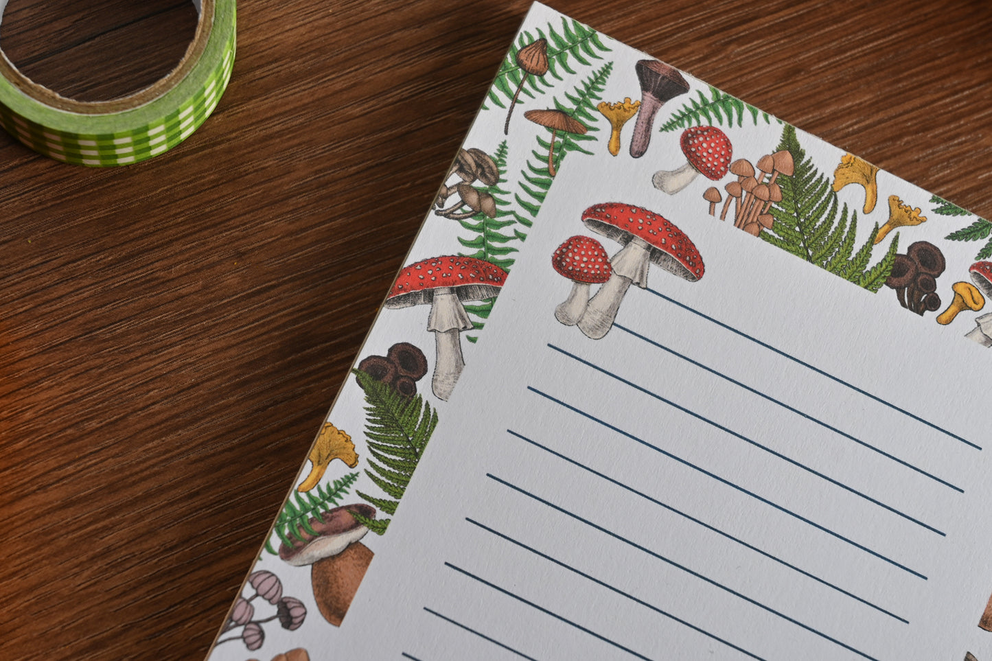 photo featuring a notepad illustrated with wild mushrooms and fern, corner close up