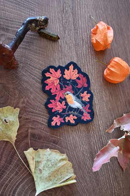 Decorative sticker with a bird and leaves on a wooden surface with fall elements.