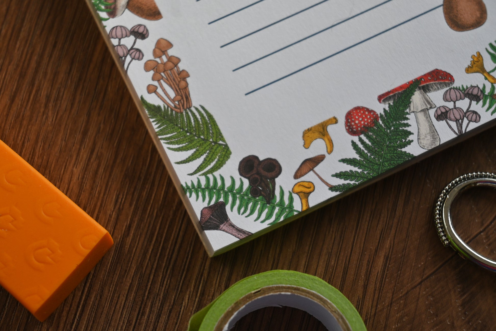 photo featuring a notepad illustrated with wild mushrooms and fern, corner close up