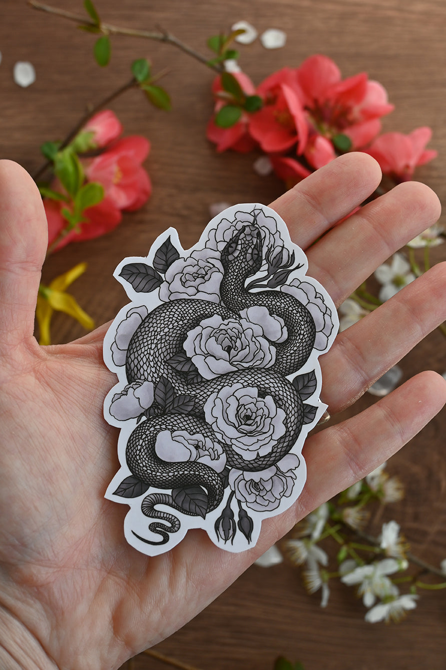 photo of a laminated paper sticker featuring illustration of a snake among rose flowers