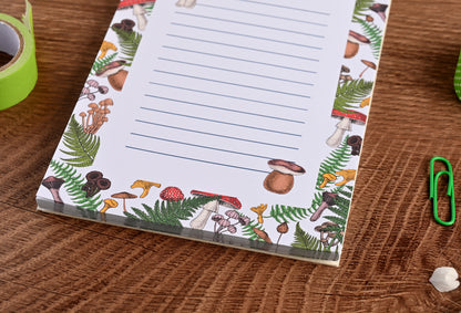 photo featuring a notepad illustrated with wild mushrooms and fern, angle view