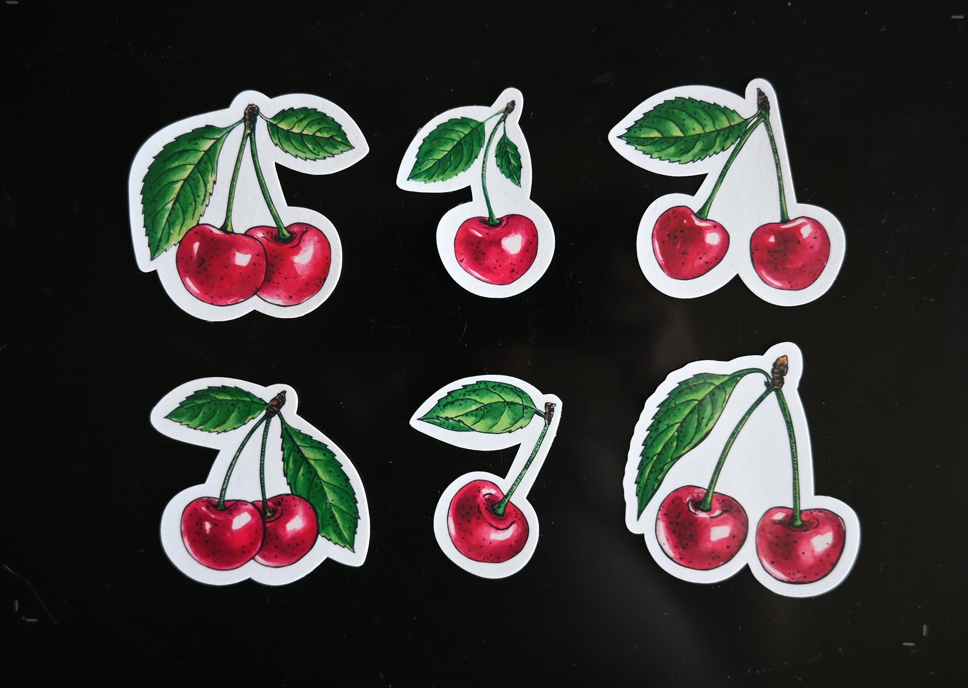 photo of 6 laminated paper stickers featuring hand- painted cherry fruits with leaves