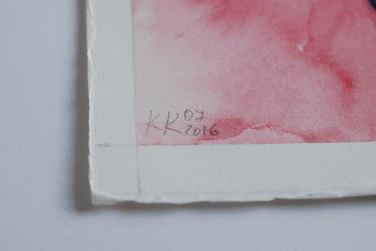 Artistic watercolor signature on a piece of paper with red and pink hues.