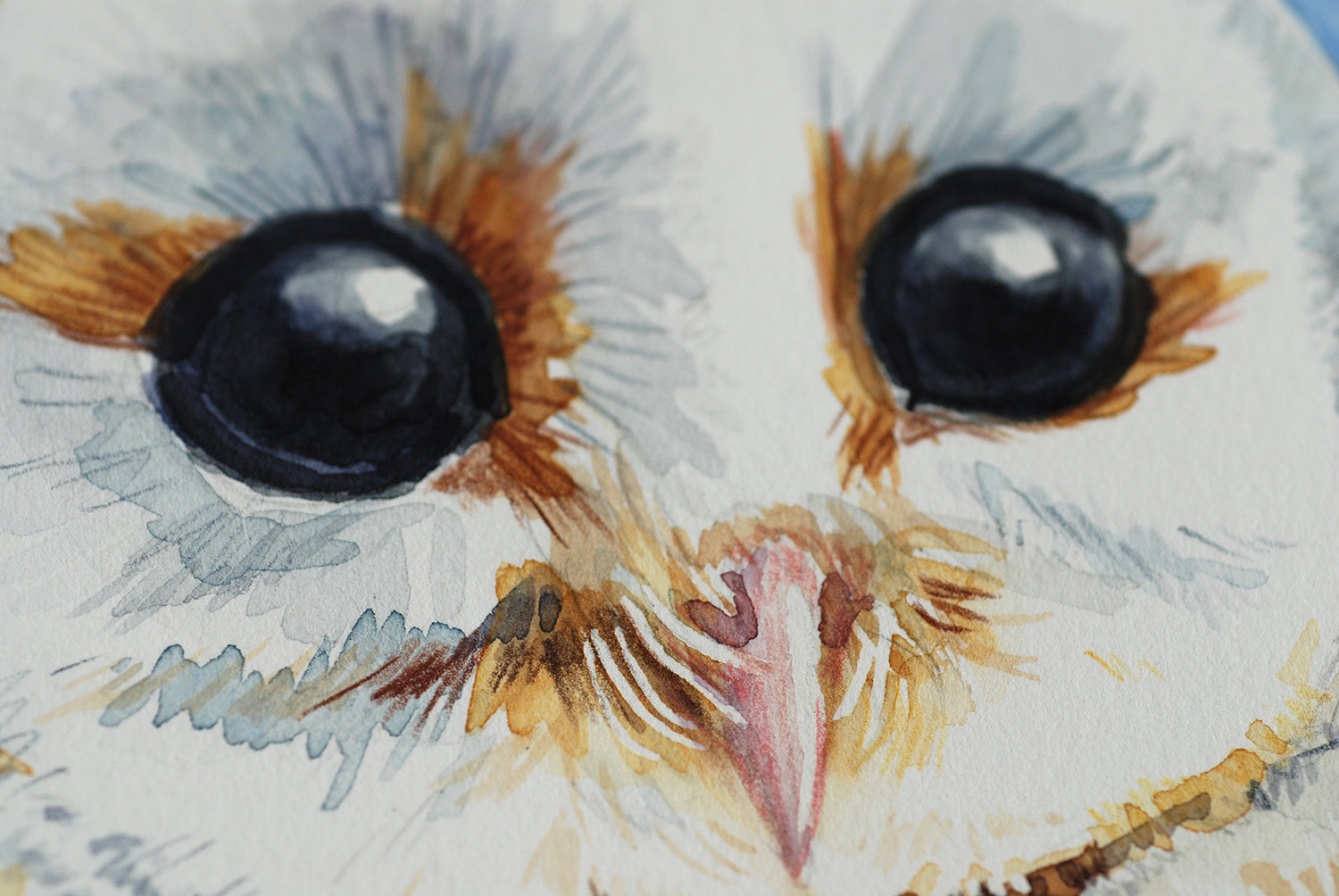 Close-up of a watercolor painting of an owl's face with large eyes and detailed feathers.