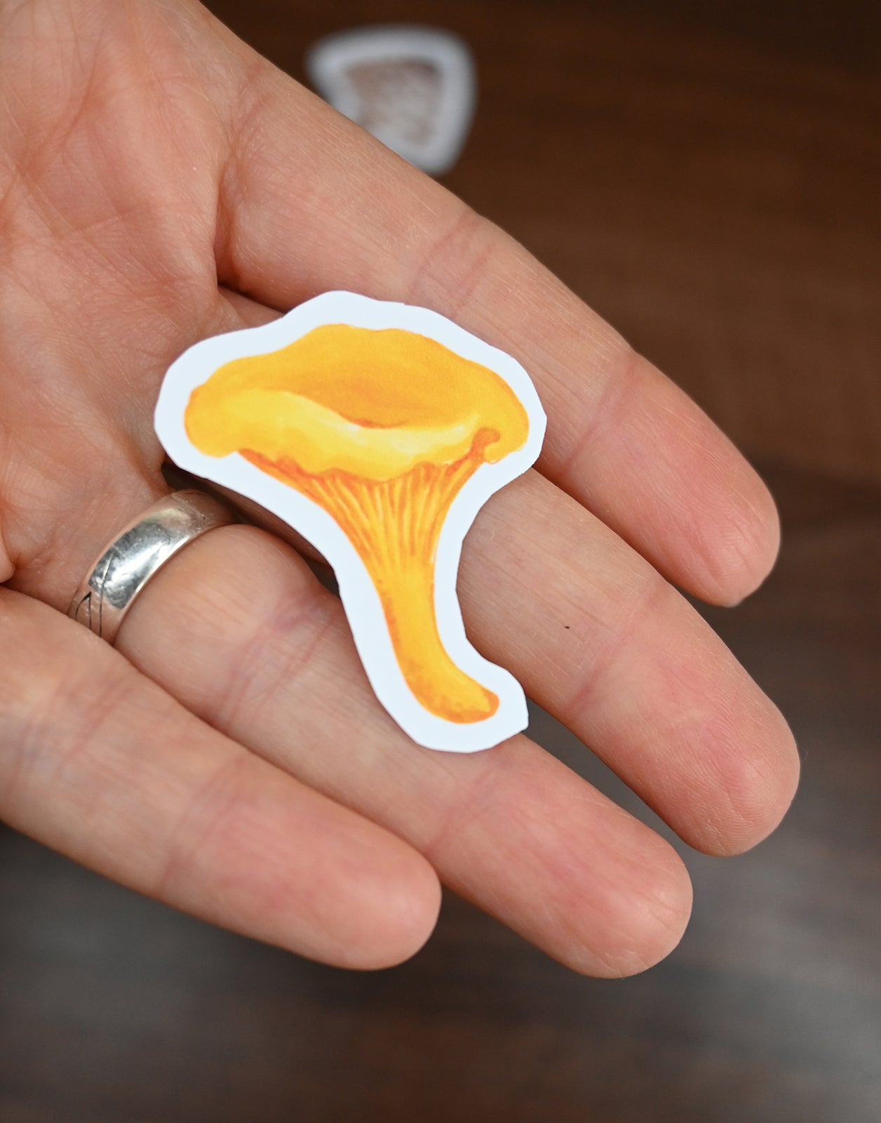 Hand holding a yellow mushroom-shaped sticker