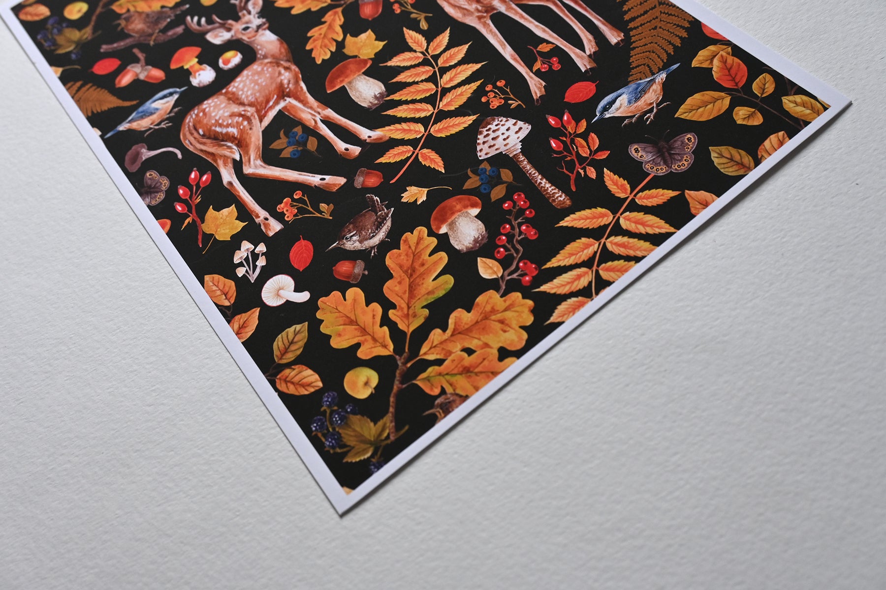 close up of the corner of print of two deer among autumnal flora, mushrooms and birds