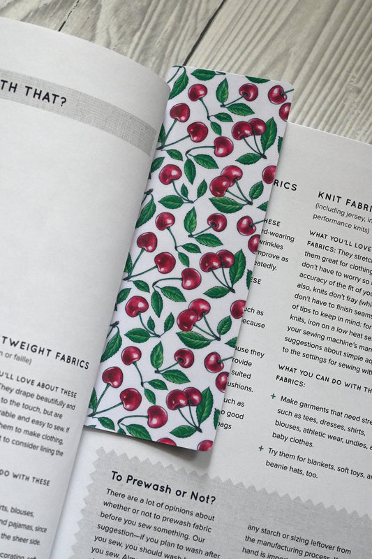 Book with a cherry-patterned bookmark on a wooden surface
