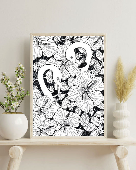 Framed black and white floral and flamingo artwork on a shelf with decorative items.