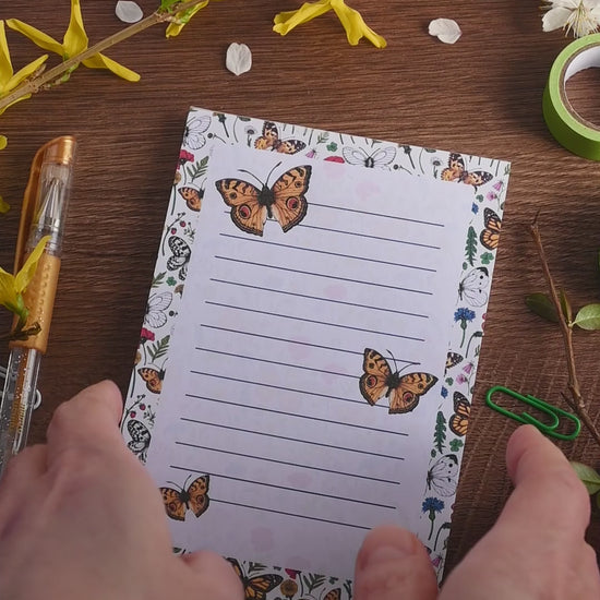 video featuring a notepad illustrated with wildflowers and butterflies