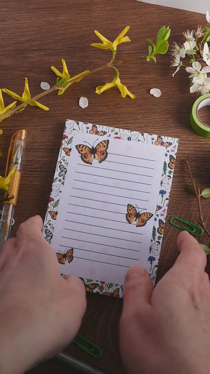 video featuring a notepad illustrated with wildflowers and butterflies