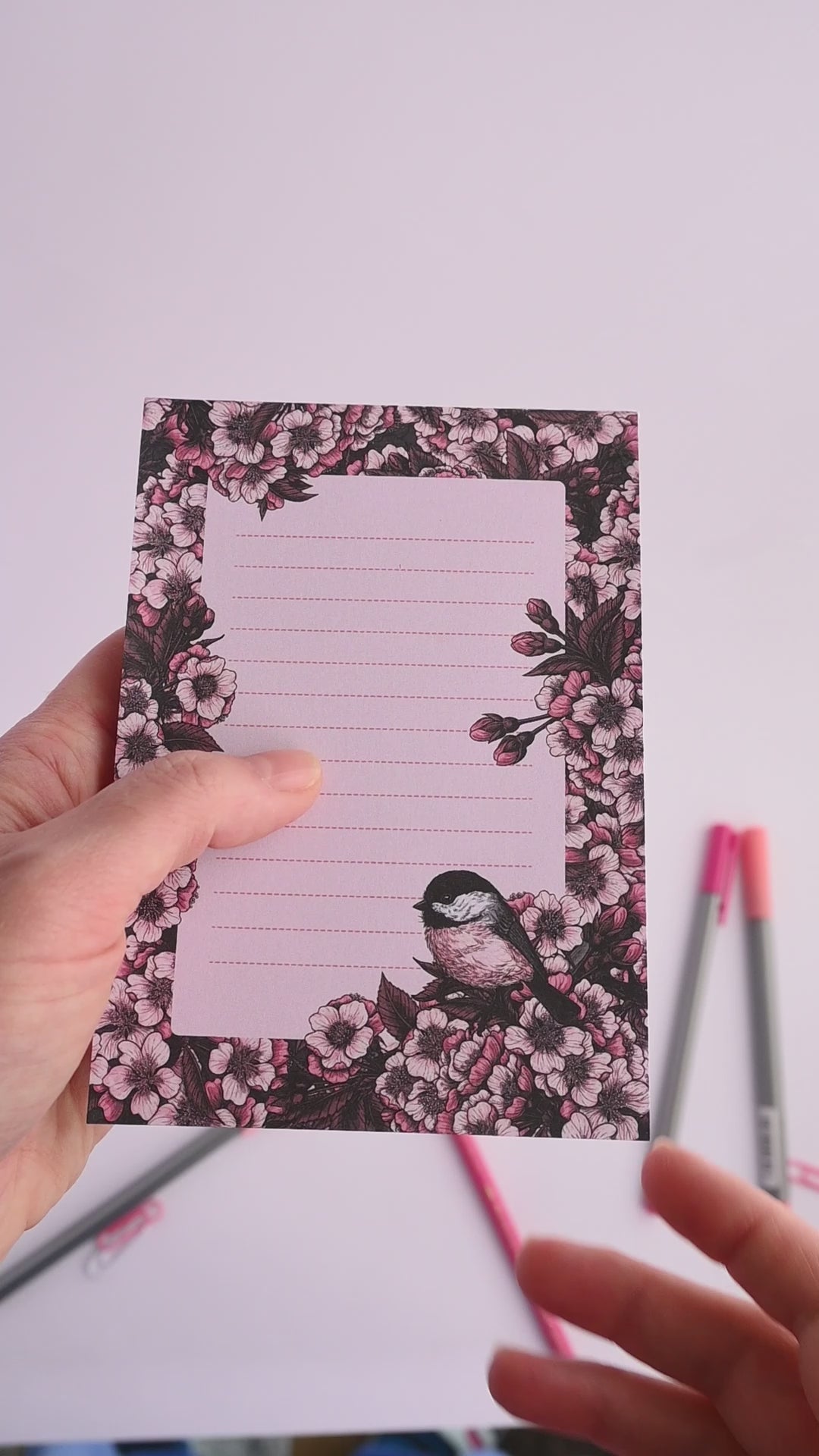 video of notepad featuring hand painted frame of cherry blosssom and chicakee bird in the lower right corner and  lined middle