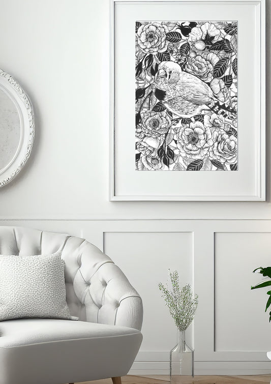 Framed ink painting in black and white roses and bird illustration above a white sofa.
